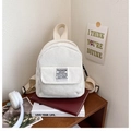 Detail view of cream corduroy texture and fashion woven label on small backpack - White