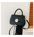 Minimalist black matte crossbody bag with a textured gold round buckle and top handle - Black