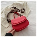Red semicircular saddle bag with a colorful striped wide shoulder strap on a beige blazer - Red