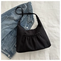 Close-up of black pleated nylon hobo bag with front pocket detail on denim background - Black