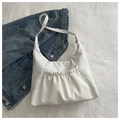 Close-up of a white pleated crossbody bag with drawstring pockets on blue denim fabric - White