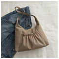 Detail of khaki pleated crossbody tote bag styled on white fabric with blue denim jacket - Khaki