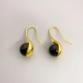 Detailed close-up of gold-plated drop earrings featuring black agate and white pearl accents - Gold + Black Agate