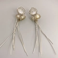 Boucles d'oreilles fleurs argentées à pompons avec perles et strass sur fond gris - Or blanc