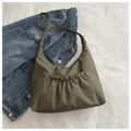 Detail of olive green nylon hobo bag with pleated front pocket on denim jacket - Green