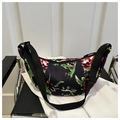 Close-up of crescent bag with floral print, adjustable strap and smooth fabric texture - Black