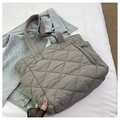 Detail of grey quilted nylon puffer tote bag featuring diamond pattern on denim background - Gray