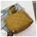 Close-up of mustard yellow quilted nylon tote bag with classic diamond stitch pattern - Yellow