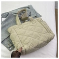 Top view of beige quilted nylon tote bag with rhombus pattern on denim shirt background - Off White