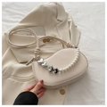 Detail of off-white saddle bag with silver heart pearl chain on a stylish blazer background - White