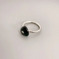 Makro-Detail des silbernen Rings mit schwarzem Emaille-Herz auf grauem Hintergrund - Silber + Schwarz