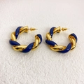 Dettaglio di orecchini a cerchio a C intrecciati in smalto blu scuro e oro su fondo bianco - Blu