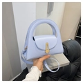 Detail of light blue leather handbag with unique gold geometric clasp and ring handle - Blue
