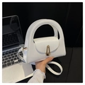 Close-up of white patent leather handbag with gold geometric buckle and handle - White