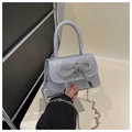 Sac argenté scintillant avec nœud en strass et chaîne métallique tenu à la main - Argent
