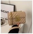 Close-up of beige quilted crossbody bag with golden geometric lock and chain strap - Khaki