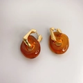 Detail of irregular U-shaped gold earrings with amber resin pendant charms - Brown