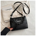 Detail of black faux leather shoulder bag with chain strap and fashion label on blazer - Black