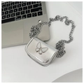 Silver mini crossbody bag with butterfly detail and metal chain on a desk - Silver