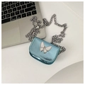 Vue détaillée du mini sac bleu métallisé avec motif papillon à côté d'un ordinateur - Bleu