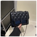 Detailed close-up of classic black quilted shoulder bag with metal chain strap and flap closure - Black