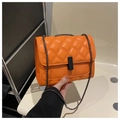 Detailed shot of bright orange quilted crossbody bag with black metal lock and chain strap - Orange