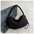 Borsa hobo minimalista in nylon nero con coulisse e tracolla larga su denim chiaro - Nero