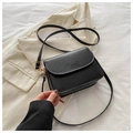 Detalle de bolso bandolera de cuero negro con herrajes dorados sobre blazer blanco - Negro