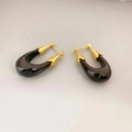 Pendientes en forma de U de resina negra con tapas doradas sobre un fondo beige - Negro
