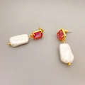 Dettaglio macro di orecchini con perle barocche, pietre preziose rosse e montatura dorata lucida - Oro Zirconia Rossa