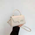 Dettaglio borsa in pelle color crema con chiusura tonda dorata e manico superiore - Bianco Sporco