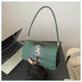 Detailed view of dark green crocodile pattern handbag with gold hardware and tassel - Green