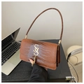 Detail of a brown crocodile texture bag featuring a golden SS logo and metallic tassels - Brown