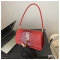Detail of red crocodile texture handbag featuring golden S-logo and metal tassel charms - Red