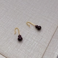 Elegant gold hook earrings featuring deep red enamel gourd pendants on a grey textured background - Brown