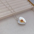 Detailed view of silver heart pendant with golden starburst and red gemstone on linen - Retro Heart Apple Pendant (Approx 74cm)