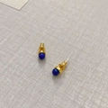 Makro-Detail vergoldeter Ohrstecker mit runden, tiefblauen Lapislazuli-Edelsteinen - Lapislazuli-Textur-Stil / Lapisblau