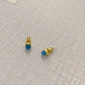 Makroansicht minimalistischer Goldohrringe mit himmelblauen Achatkugeln auf hellem Stoff - Blau-Chalcedon-Look-Stil / Himmelblau