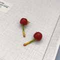Pastel cherry earrings with glossy red finish and green stems on textured paper - Cherry Studs