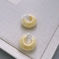 Detail von handgestrickten gelben Creolen auf einer lavendelfarbenen Schachtel - Käse
