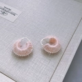 Details von rosa handgewebten Garn-Ohrringen mit versilberten Haken und weicher Fasertextur - Creme