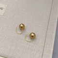 Dettaglio ravvicinato di orecchini a perla dorata da 12mm con eleganti ganci in metallo - Oro
