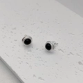 Macro shot of silver stud earrings with black onyx stone inlay and textured border - Black Agate