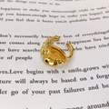 Dettaglio di un anello dorato regolabile con texture lava su una pagina di libro - Misura aperta 7 / Oro 18K