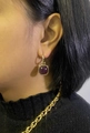 Detail of vintage gold earrings with square purple gemstone on a female model - Purple