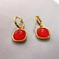 Detailed macro view of cushion-cut red gemstone drop earrings with gold-plated finish - Red