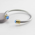 Detalle del brazalete de cable de acero inoxidable trenzado con anillos de oro y piedras - Plata/Oro (Piedra Azul)