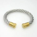 Macro view of cable wire bangle with silver braided steel and matte gold caps - Gold/Steel