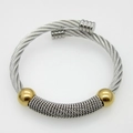 Détail d'un bracelet câble torsadé en acier avec bande argentée et perles dorées - Or et Acier