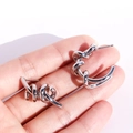 Polished silver twisted knot earrings with asymmetric wrap design held by hand - Silver